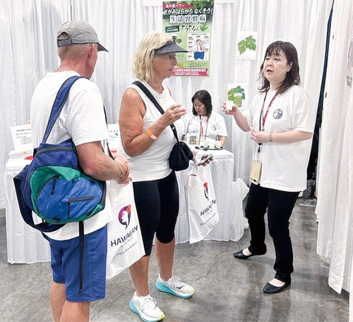 ブースを訪れた参加者に桑茶を紹介する猪熊美奈子さん（右）