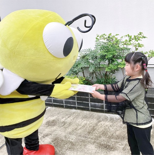 プレゼントを届けに来た「ぶんちゃん」にお礼の色紙を手渡す子ども