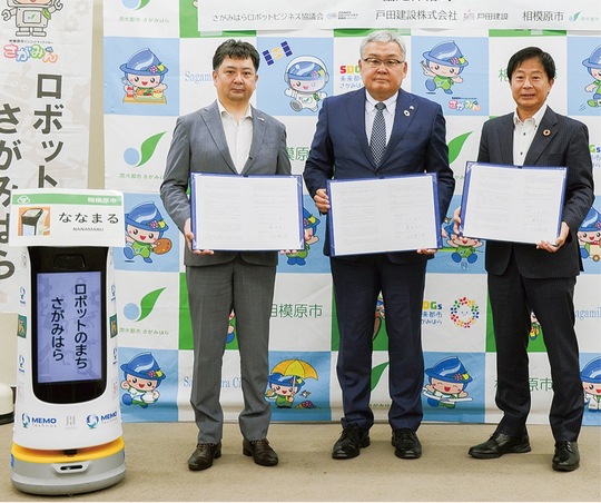 （左から）締結式に出席したロボット職員「ななまる」、藤本会長、大谷社長、奈良副市長