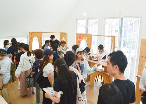 三角屋根の下来場者でにぎわうブース