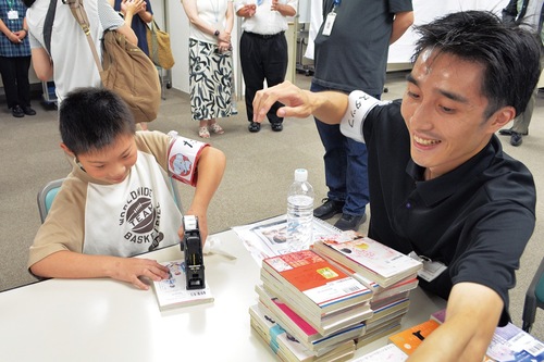 本に値段シールを貼る仕事体験の様子。作業のあまりの速さに運営スタッフが慌てている