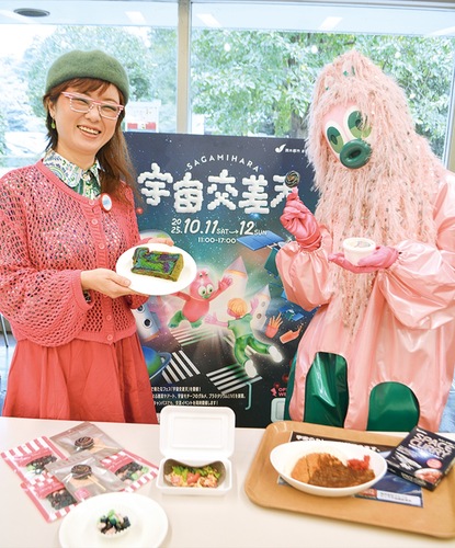 宇宙グルメを手にするイベントの公式マスコット「ぎゃみみ」（右）と、ぎゃみみをイメージした装いのインフルエンサー、飯田さくらさん（＠sakurahuwari415）。１日に行われた先行体験会で