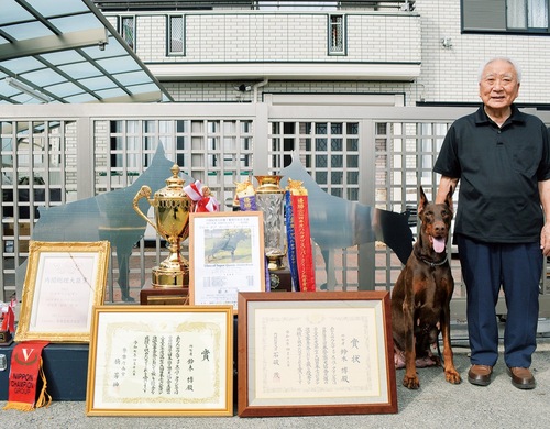 愛犬・ウルマと共に、今回授与された数々の賞状やトロフィーを前に笑顔の鈴木さん