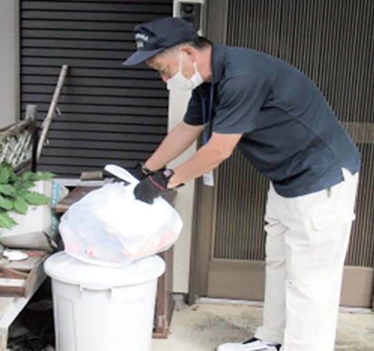 玄関先に出されたごみを収集する職員