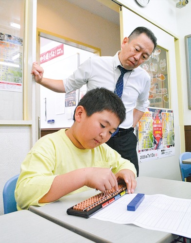 ５分で４桁×４桁までのかけ算を30問解いてみせた美濃部さんと、様子を見守る講師の下地さん