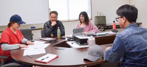 甲斐社長、広報・開発部の担当者と新商品のアイデアを考える生徒（右）