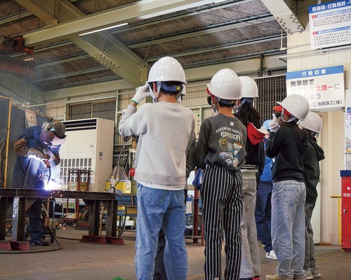 遮光メガネをかけて溶接の作業を見学する児童たち