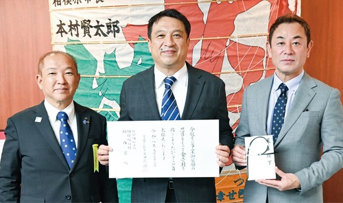 伝達式の様子＝同法人提供。左から本村賢太郎市長、下山正明施設長、赤間源太郎理事長