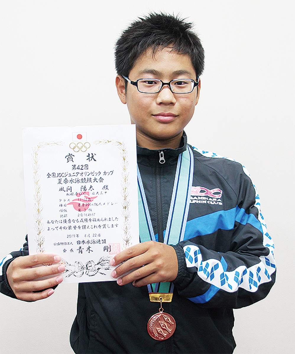 メダルを首にかけ賞状を掲げる風間さん＝8月29日、相模原ドルフィンクラブ