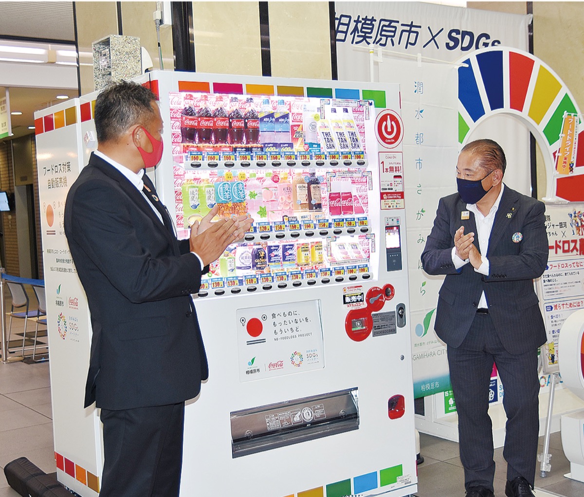 フードロス対策自販機の前で拍手を送る本村市長と市川部長=4日
