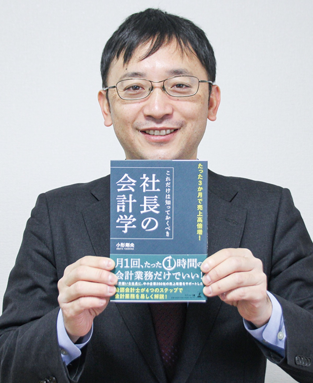 書籍を紹介する小形会計事務所の小形所長＝4日、横山台の事務所で
