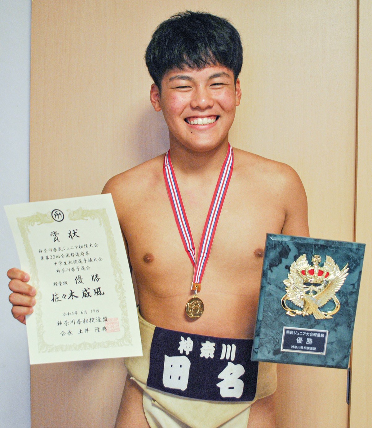 賞状と盾を手にし、金メダルをかけた佐々木さん