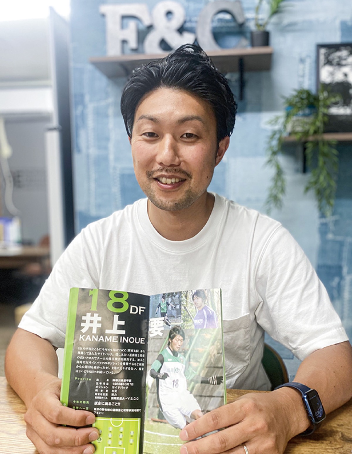 内装業で起業した井上さん。当時のチーム紹介紙の自分のページを広げる