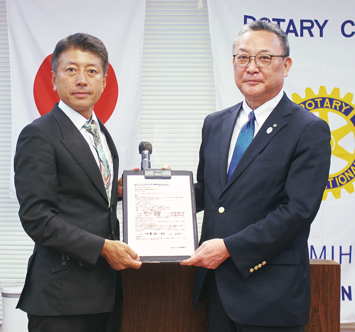 署名した新クラブ申請書を手にする野々山会長（左）と佐藤ガバナー
