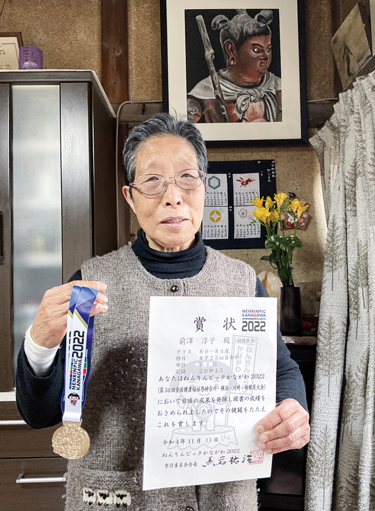 ねんりんピックかながわの賞状と金メダルを手に。上に飾ってあるのは自身の水彩画作品＝2月8日