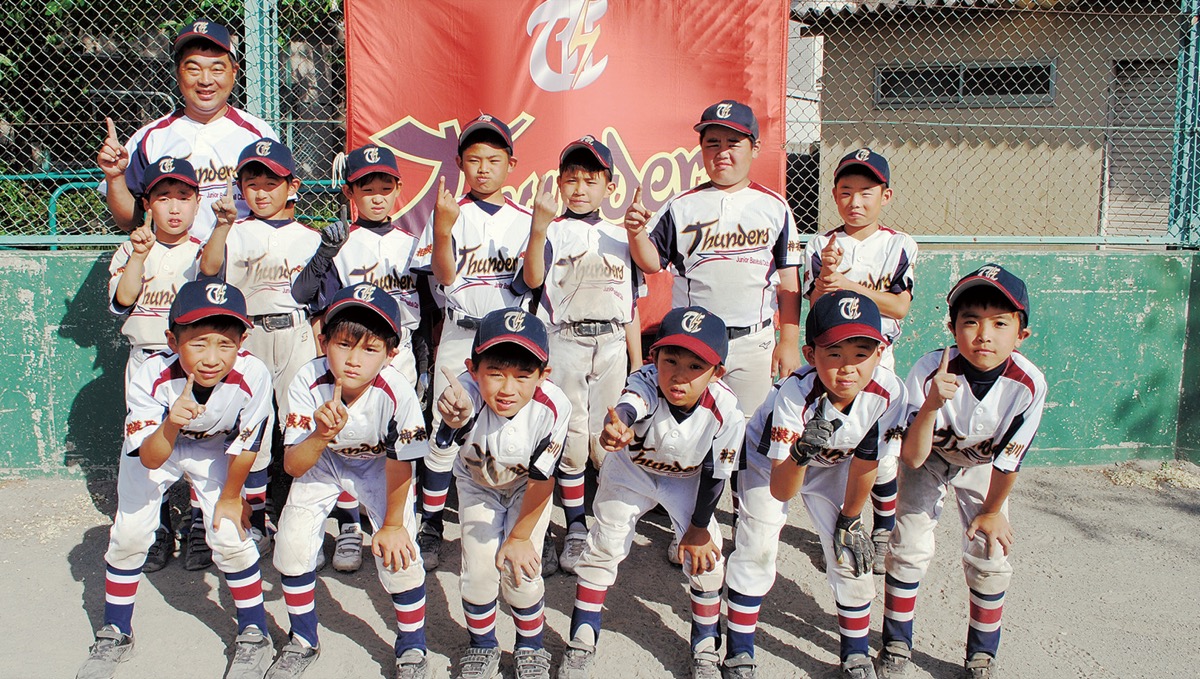 「目指せナンバーワン！」とポーズを決める低学年チームの選手たちと成井監督