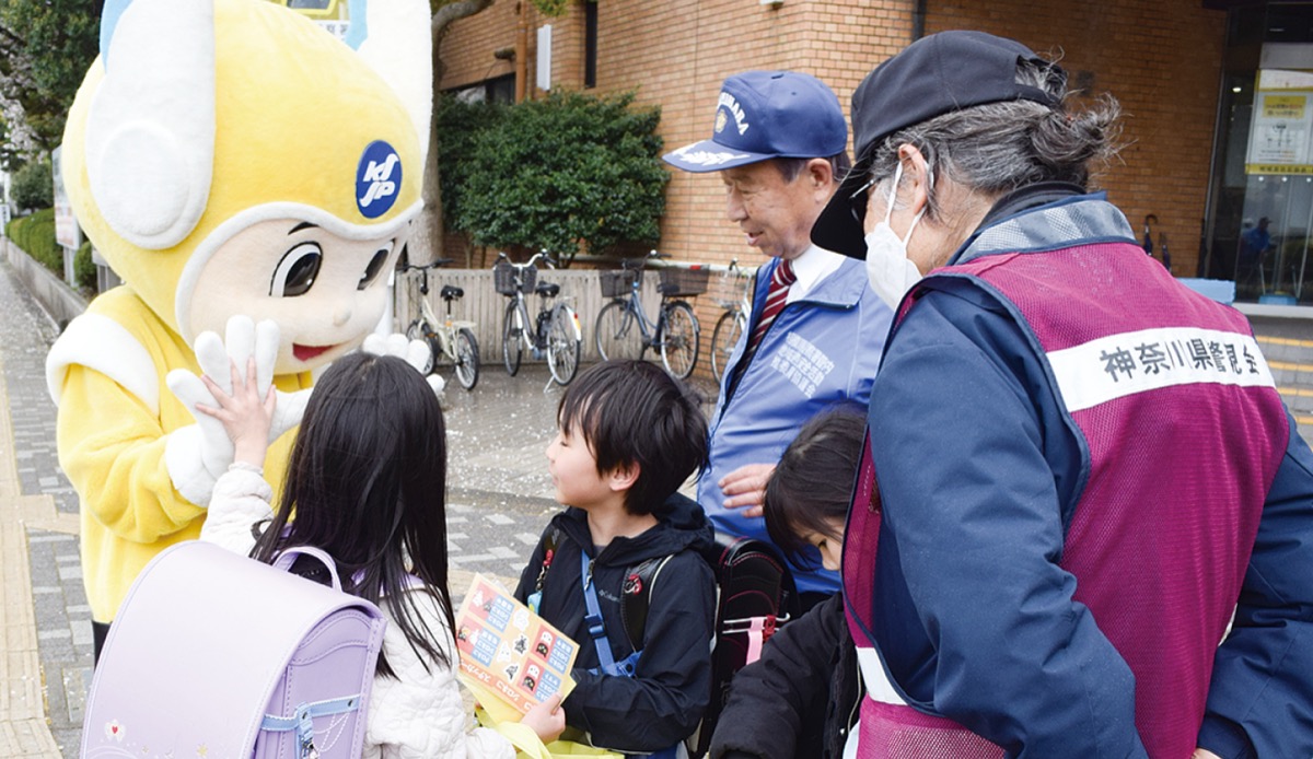 啓発グッズを受け取り「ピーガルくん」（左）とハイタッチする子どもたち