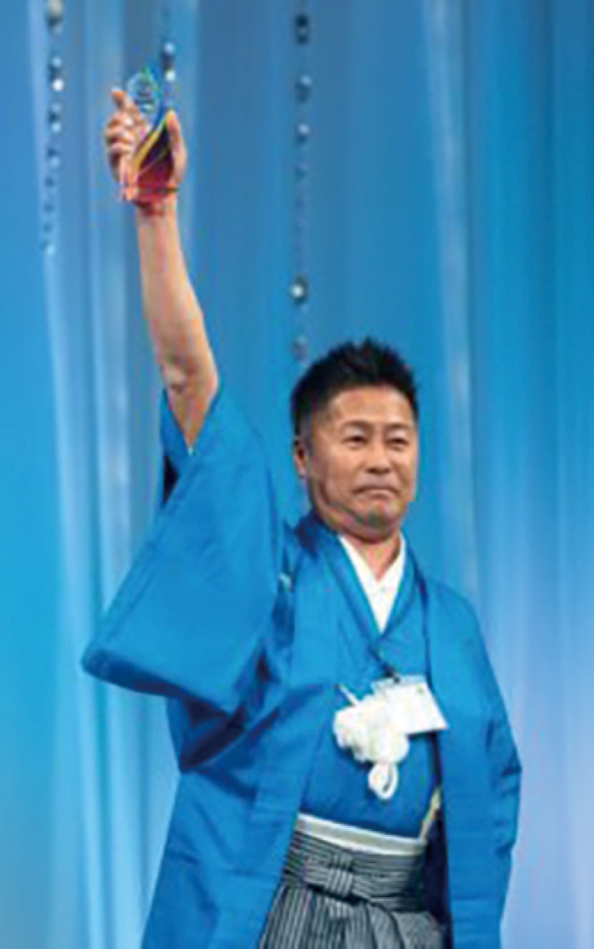 過去の表彰式でトロフィーを掲げる中村社長