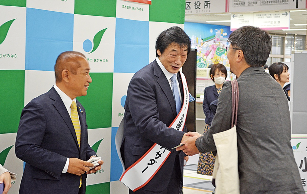 式後に早速アンバサダーの名刺とポケットティッシュを訪れた市民、ファンに手渡す小橋さん（中央）