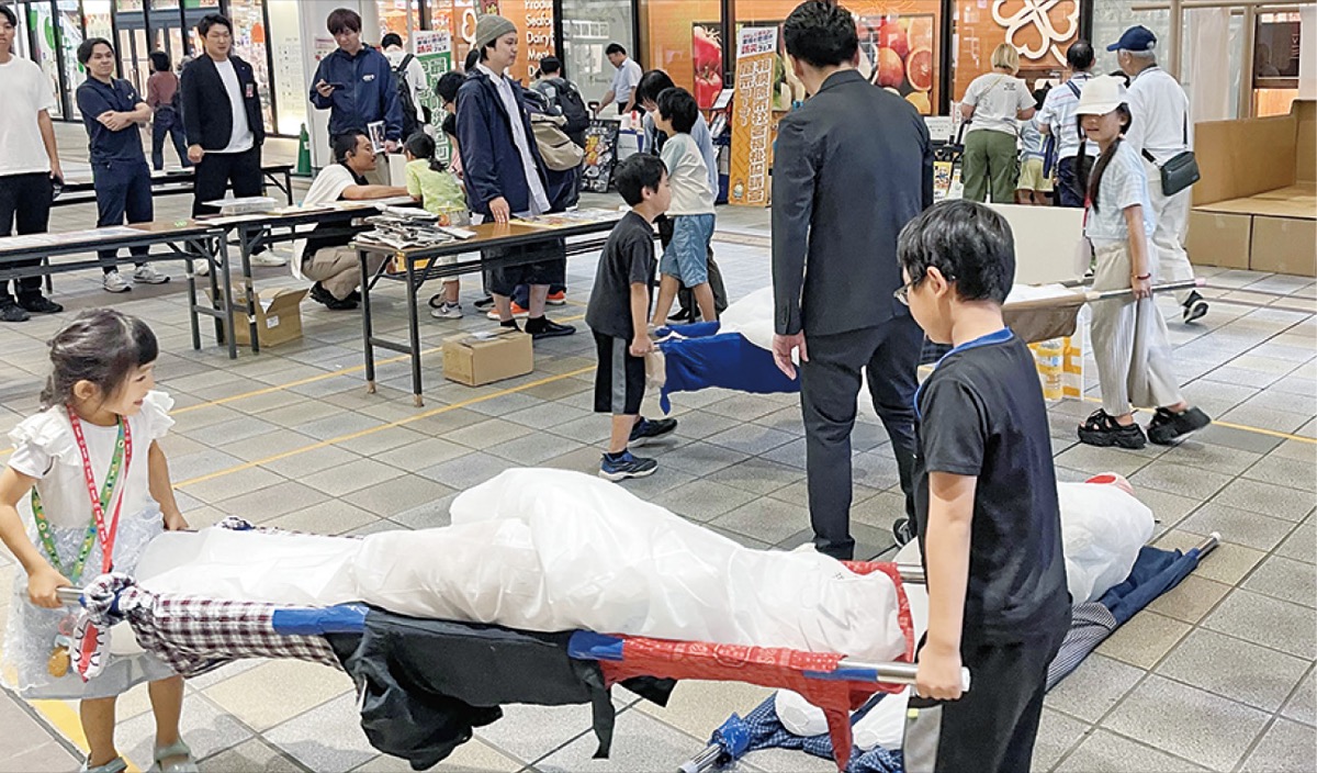 負傷者を模した人形を運び「共助」を学ぶ体験も