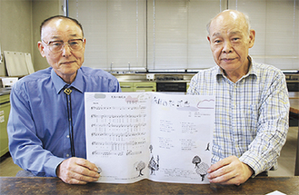 歌詞カードを手にする平片委員長（左）と小林勉副委員長