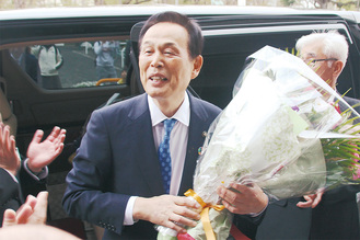 市職員や市民に見送られ、花束を抱えて謝辞を述べる加山俊夫市長＝19日、市役所正面玄関前で