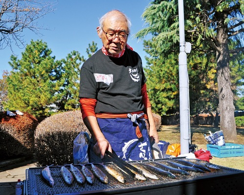 慣れた様子でさんまを焼く笹本さん