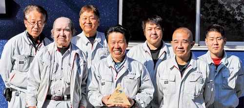 認証の盾を持つ小池さんと社員の皆さん