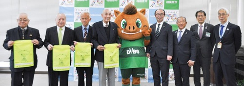 ランドセルカバーを手にする交通安全協会の会長たちと｢ダイボ君｣（中央）、本村市長（右から３人目）