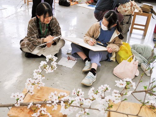 桜を前に交流を深める学生と小学生