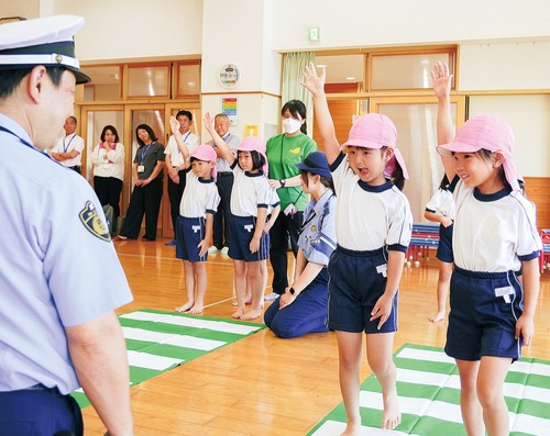 運転手が確認できるよう手を挙げて横断歩道を渡る練習をする園児