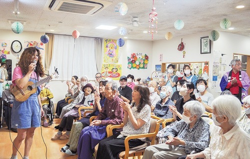 タブレット純さん（左）の歌を楽しむ利用者と家族