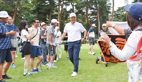 声援を受け、1番ホールのティーイングエリアへ向かう原さん（中央）。18日撮影