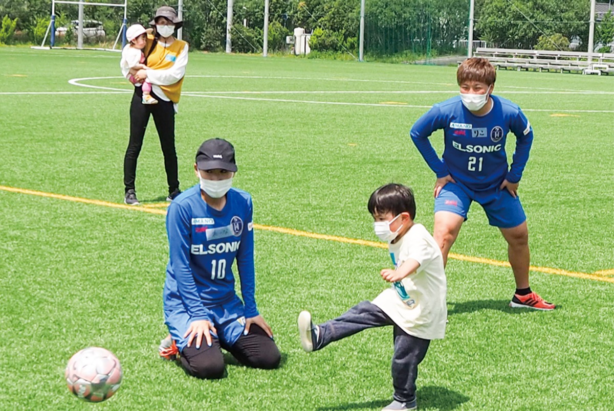 シュート練習をする児童と見守るノジマの選手