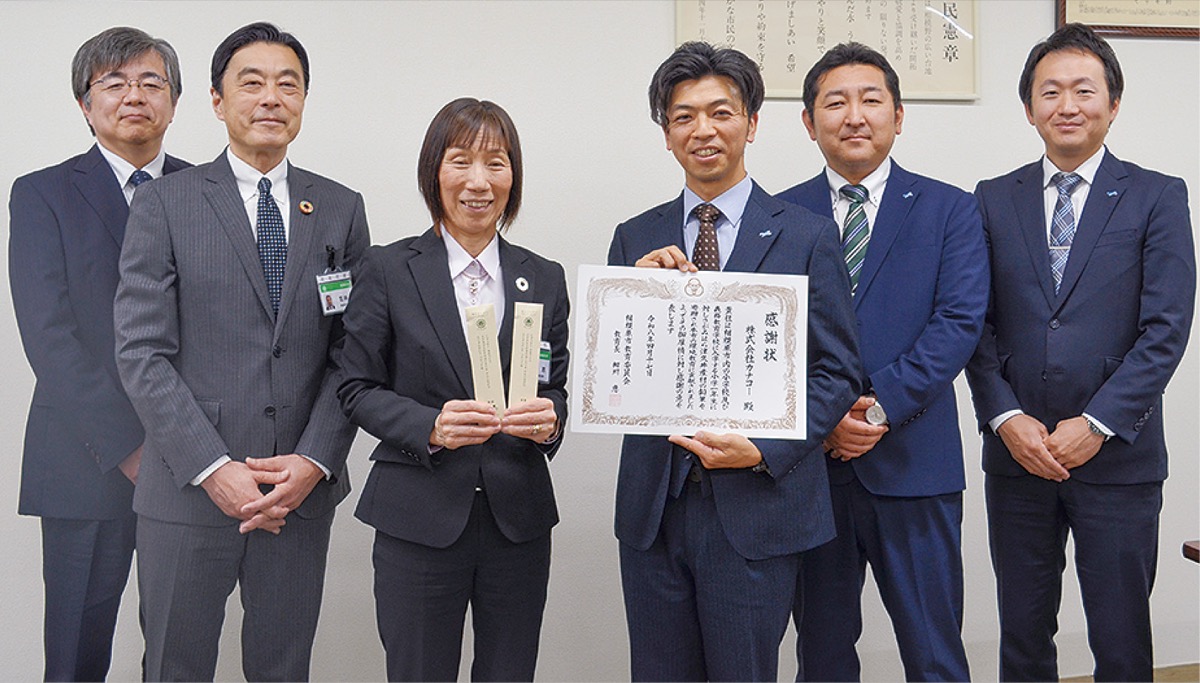 大久保代表と細川教育長（中央）、同社社員、市職員ら