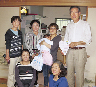 プレゼントを受け取った200人目の赤ちゃん・藤本栞ちゃんを囲む民生・児童委員、主任児童委員ら