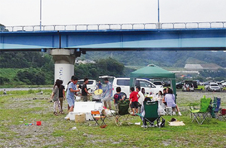 高田橋付近の河川敷でバーベキューを楽しむ人々＝バーベキュー・ジャパン提供