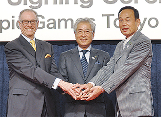 手を取り合う（左から）カルロス・ヌズマンBOC会長、竹田恆和JOC会長、加山俊夫市長