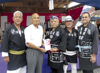 寄付を受け取る今井会長（左から2番目）と皇の人たち