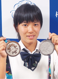 2つのメダルを手にはにかむ伊佐さん＝11日、相模女子大学中学部・高等部