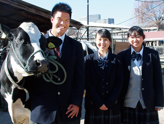 相原高校で、飼育する乳牛と一緒に撮影。左から角田さん、塗井さん、吉川さん＝1月19日