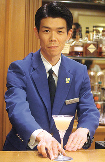 東京都知事賞のブルージャケットを着てカクテルを提供する鮎川さん