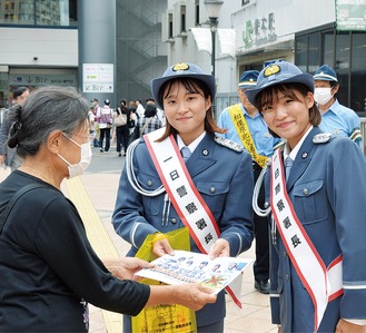 橋本駅前で啓発物を手渡す一日警察署長の宮崎若菜さん（左）と小雪さん