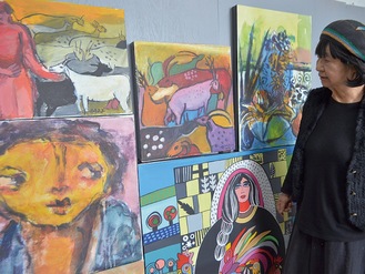 「パレスチナ支援の画家」と称されることも多い上條さん。ガザに住む作家たちの作品を見つめて神妙な面持ち（アトリエで）