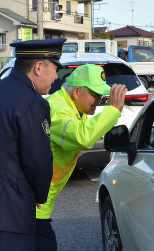 信号待ちのドライバーに呼び掛ける、山川署長（左）と平栗会長