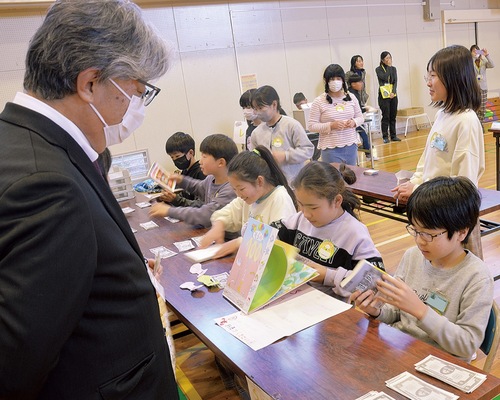 持ち込まれた本を真剣に査定する児童