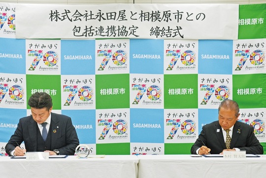 協定書にサインする本村市長（右）と田中社長