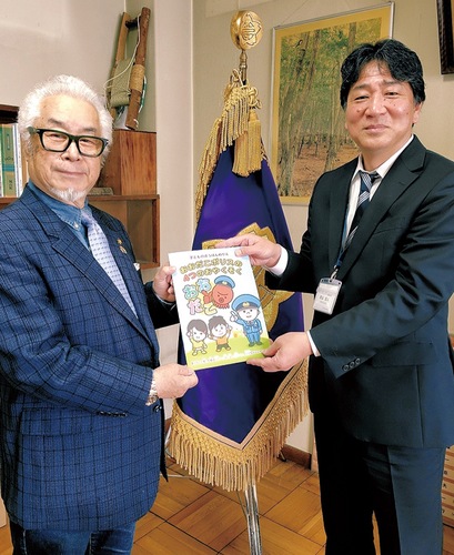 嵜山校長（右）に防犯啓発冊子を手渡す、山下会長