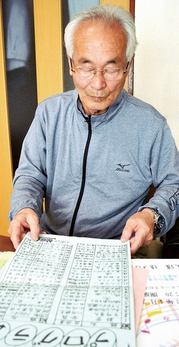 昔のプログラムを懐かしそうにながめる石川さん