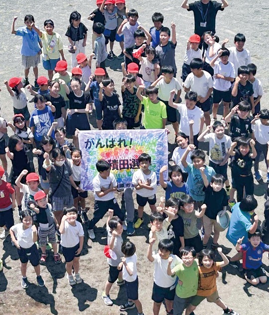 「先輩」を応援する旗を掲げエールを送る横山小の児童（写真は同校提供）